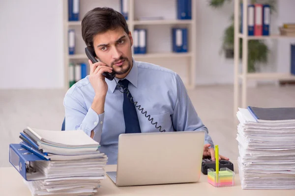 Joven empleado masculino y demasiado trabajo en la oficina — Foto de Stock