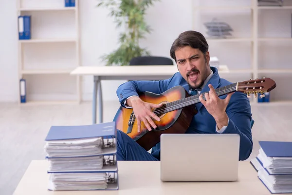 Joven empleado masculino tocando guitarra en el lugar de trabajo — Foto de Stock