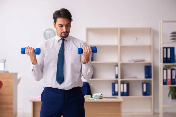 Jovem funcionário do sexo masculino fazendo exercícios esportivos durante o intervalo — Fotografia de Stock