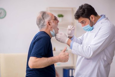 Yaşlı erkek hasta genç doktor otorhinolaryngologis 'i ziyaret ediyor.