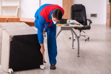 Genç erkek marangoz salgın sırasında ofiste çalışıyor.