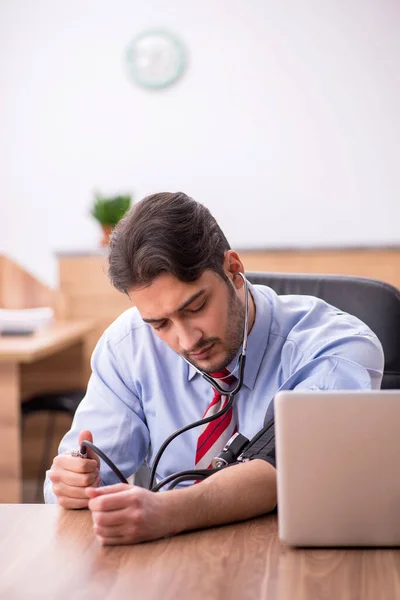 Junge männliche Mitarbeiter leiden an Bluthochdruck am Arbeitsplatz — Stockfoto
