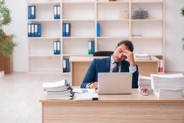 Joven empleado masculino infeliz con el trabajo excesivo — Foto de Stock