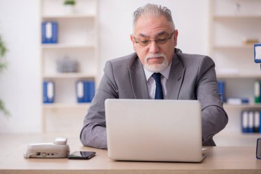 Ofisteki aşırı işten memnun olmayan yaşlı bir erkek işçi.