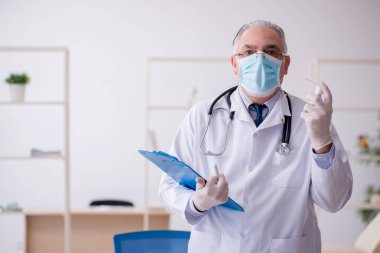 Klinikte çalışan yaşlı erkek doktor.