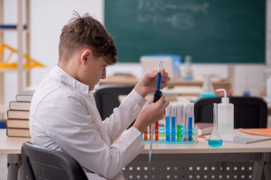 Öğrenci çocuk sınıfta kimya okuyor.