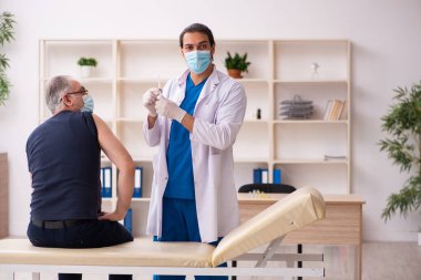Yaşlı adam covid-19 aşı konseptinde genç doktoru ziyaret ediyor.
