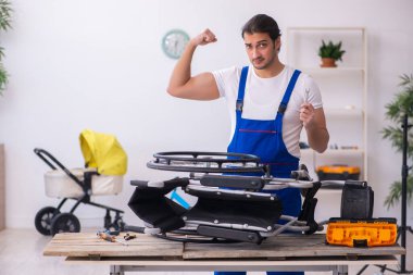 Genç erkek tamirci içeride tekerlekli sandalyeyi tamir ediyor.