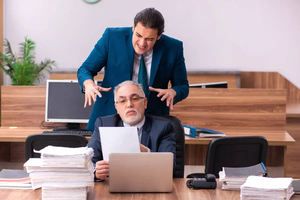 Velho empregador masculino e jovem assistente no conceito de bullying — Fotografia de Stock