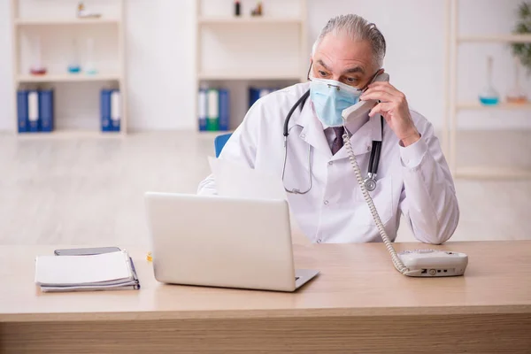 Vieux médecin masculin travaillant à la clinique pendant la pandémie — Photo