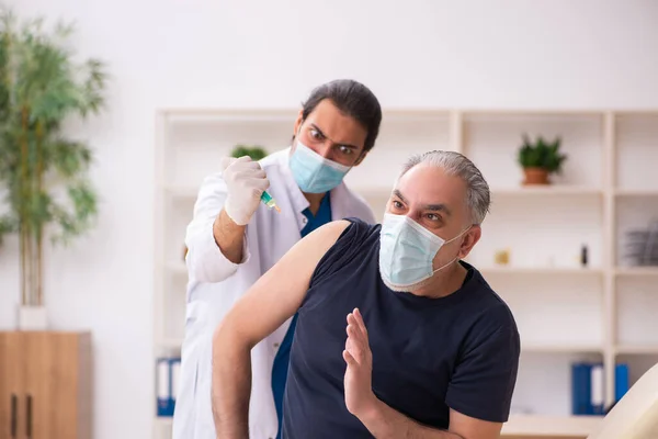 Alter Mann besucht jungen Arzt im Covid-19-Impfkonzept — Stockfoto