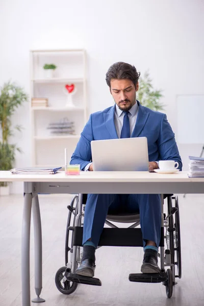 Młody mężczyzna na wózku inwalidzkim w miejscu pracy — Zdjęcie stockowe