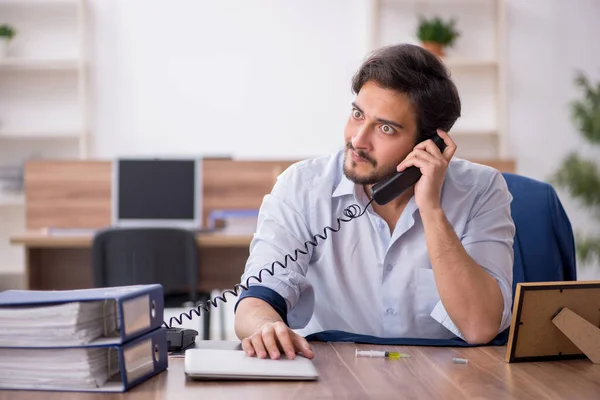 Jeune employé toxicomane masculin sur le lieu de travail — Photo