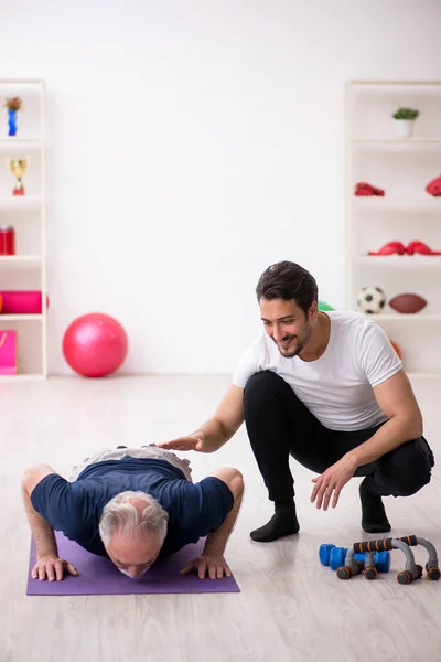 Giovane istruttore maschio e vecchio che fa esercizi sportivi — Foto Stock