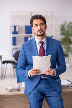 İş yerinde gazete okuyan genç bir erkek.