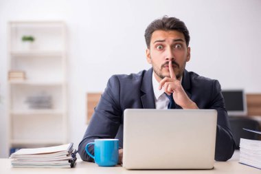 Genç erkek çalışan işyerinde oturuyor.