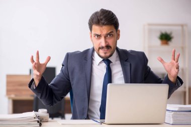 Genç erkek çalışan işyerinde oturuyor.