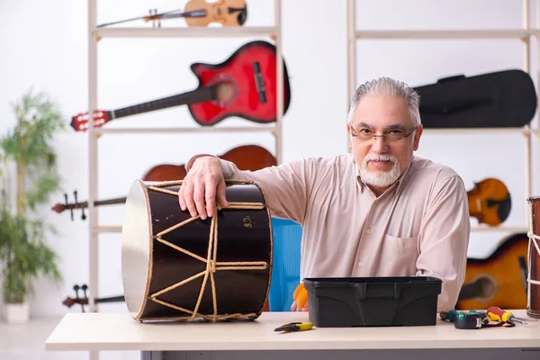 Viejo reparador masculino reparando instrumentos musicales en el lugar de trabajo —  Fotos de Stock