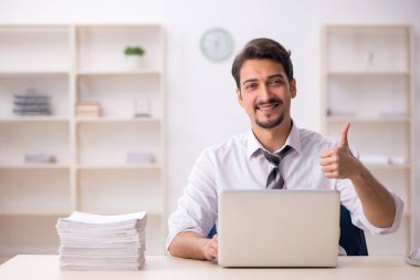 Ofisteki aşırı işten memnun olmayan genç bir erkek işçi.