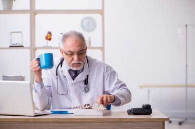 Klinikte çalışan yaşlı erkek doktor.