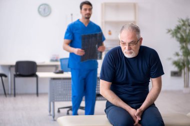 Yaşlı adam genç erkek doktor radyolojisti ziyaret ediyor.