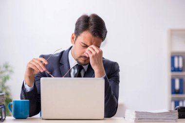 Genç erkek çalışan işyerinde oturuyor.