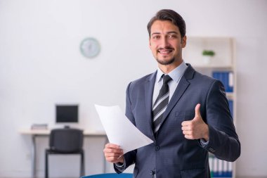 Genç erkek çalışan işyerinde oturuyor.