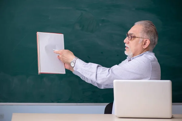 Gammal manlig lärare framför green board — Stockfoto