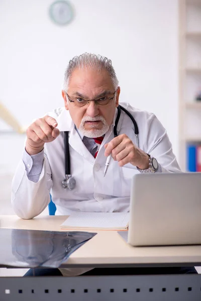 Oude mannelijke arts werkzaam in de kliniek — Stockfoto