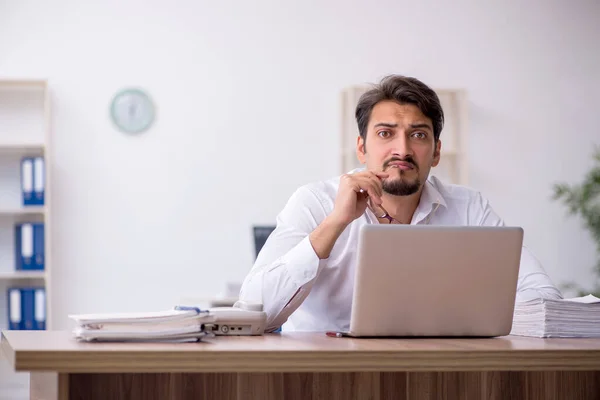 Jovem funcionário masculino e muito trabalho no escritório — Fotografia de Stock