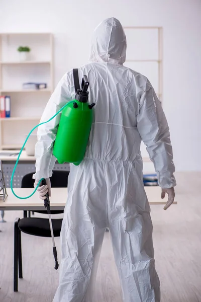 Contratista masculino joven desinfectando oficina durante pandemia — Foto de Stock