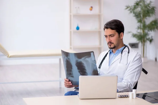 Jonge mannelijke arts in rolstoel werkzaam in de kliniek — Stockfoto