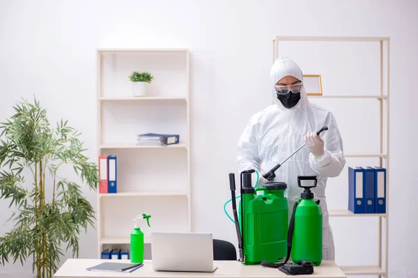 Jovem empreiteiro masculino desinfetando escritório durante pandemia — Fotografia de Stock