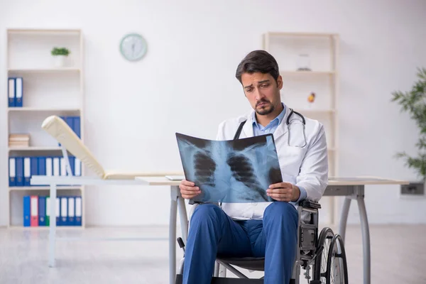 Ung manlig läkare i rullstol arbetar på kliniken — Stockfoto