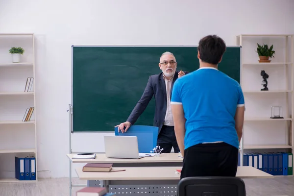 Oude mannelijke leraar en jonge mannelijke student voor schoolbord — Stockfoto