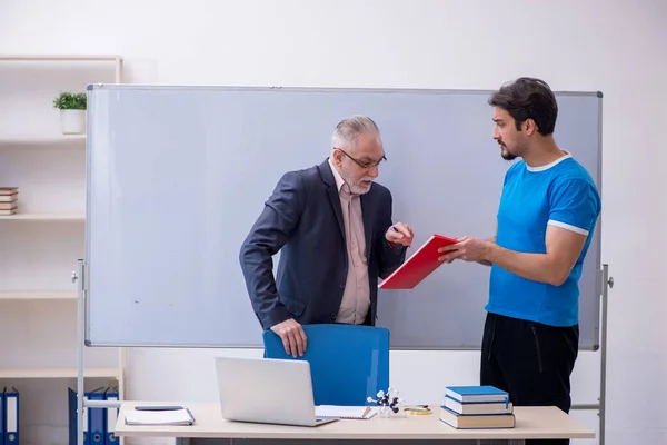 Starý muž učitel a mladý muž student v přední části tabule — Stock fotografie