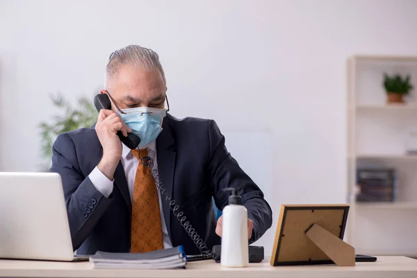 전염병 이 창궐하는 동안 사무실에서 일하는 나이든 남성 고용인 — 스톡 사진