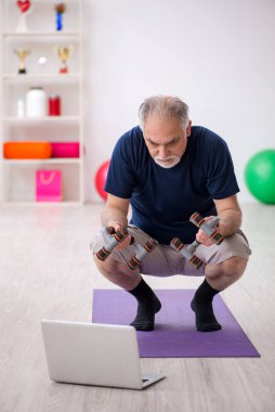 Yaşlı adam içeride spor egzersizleri yapıyor.