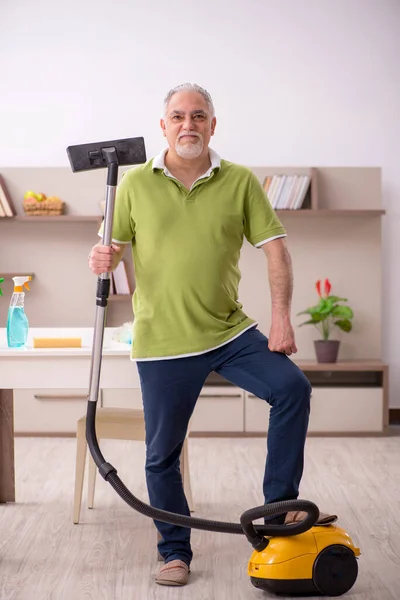 Oude man die het huis schoonmaakt — Stockfoto