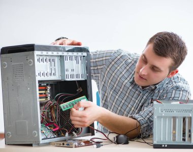 Genç teknisyen atölyede bilgisayar tamir ediyor.