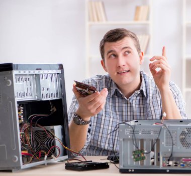 Genç teknisyen atölyede bilgisayar tamir ediyor.