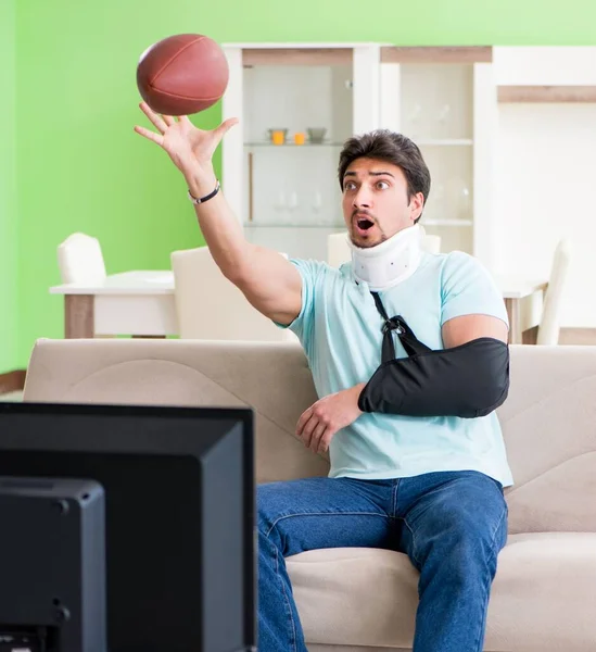 Homem com lesão no pescoço e braço assistindo futebol americano na tv — Fotografia de Stock