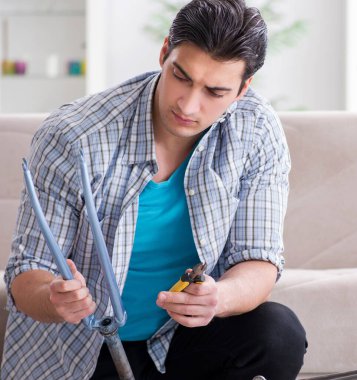 Evde bisiklet tamir eden genç bir adam.