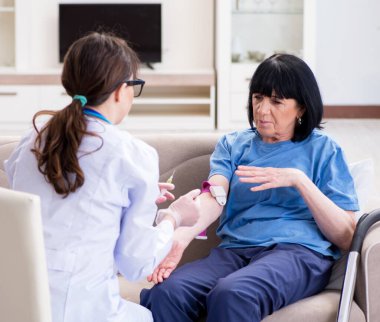 Doktor yaşlı kadına iğne yapıyor.