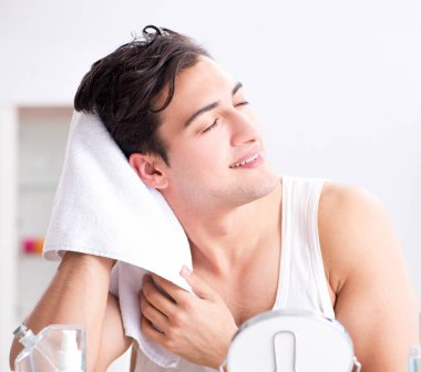 Genç yakışıklı adam aynaya bakıyor.