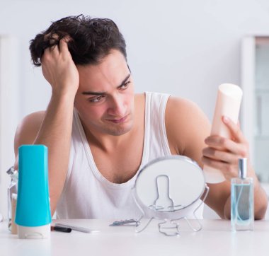 Genç yakışıklı adam aynaya bakıyor.