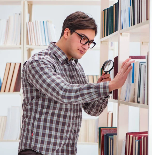 Jovem estudante procurando livros na biblioteca da faculdade — Fotografia de Stock