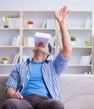 Evde sanal gerçeklik gözlüklü bir adam oynuyor.