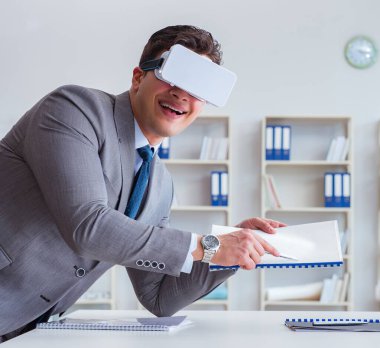 Ofiste sanal gerçeklik gözlüklü bir iş adamı var.