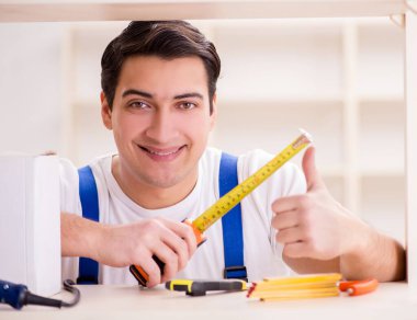 İşçi adam montaj kitaplığını tamir ediyor